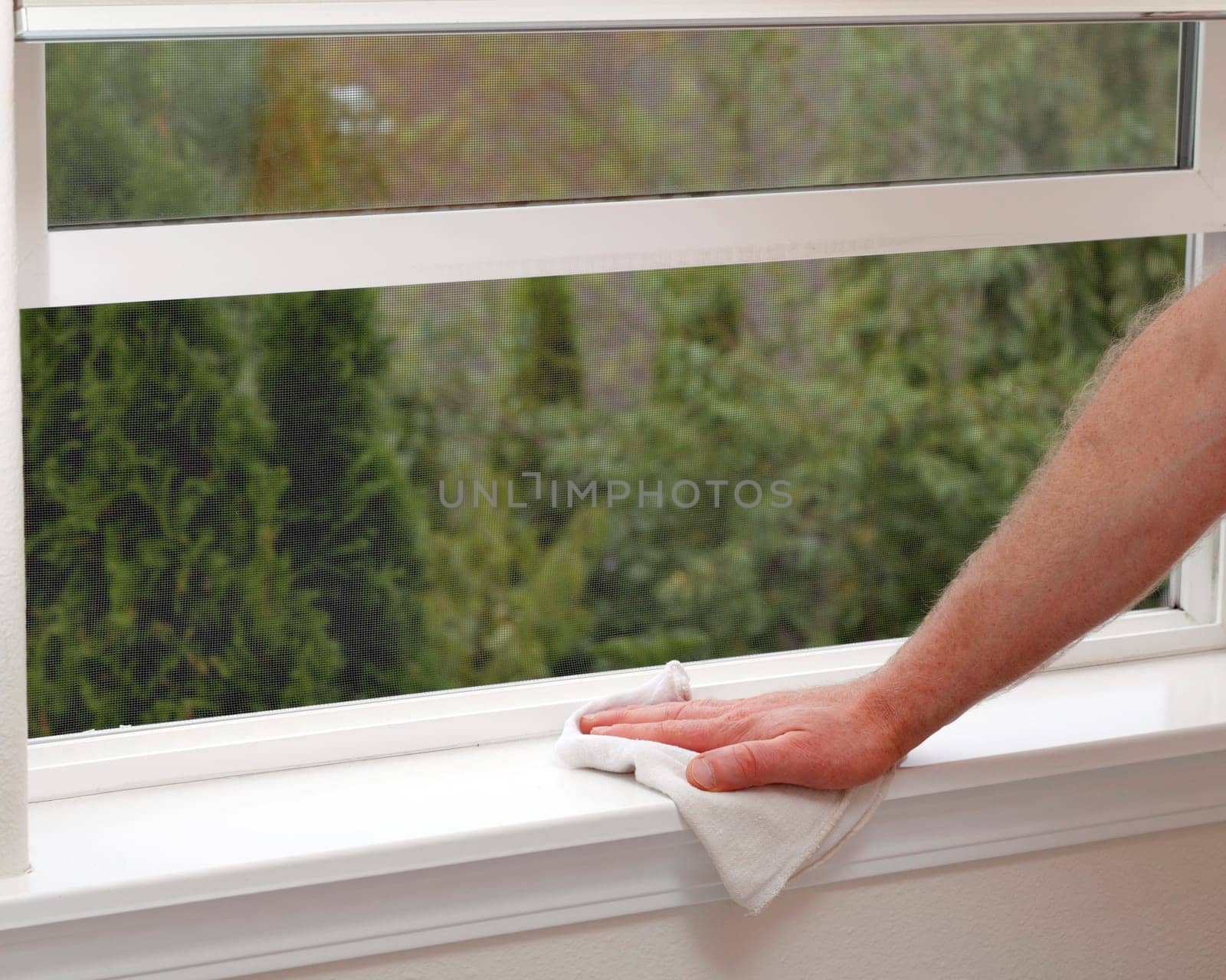 Hand dusting a window sill to reduce allergens in the home.