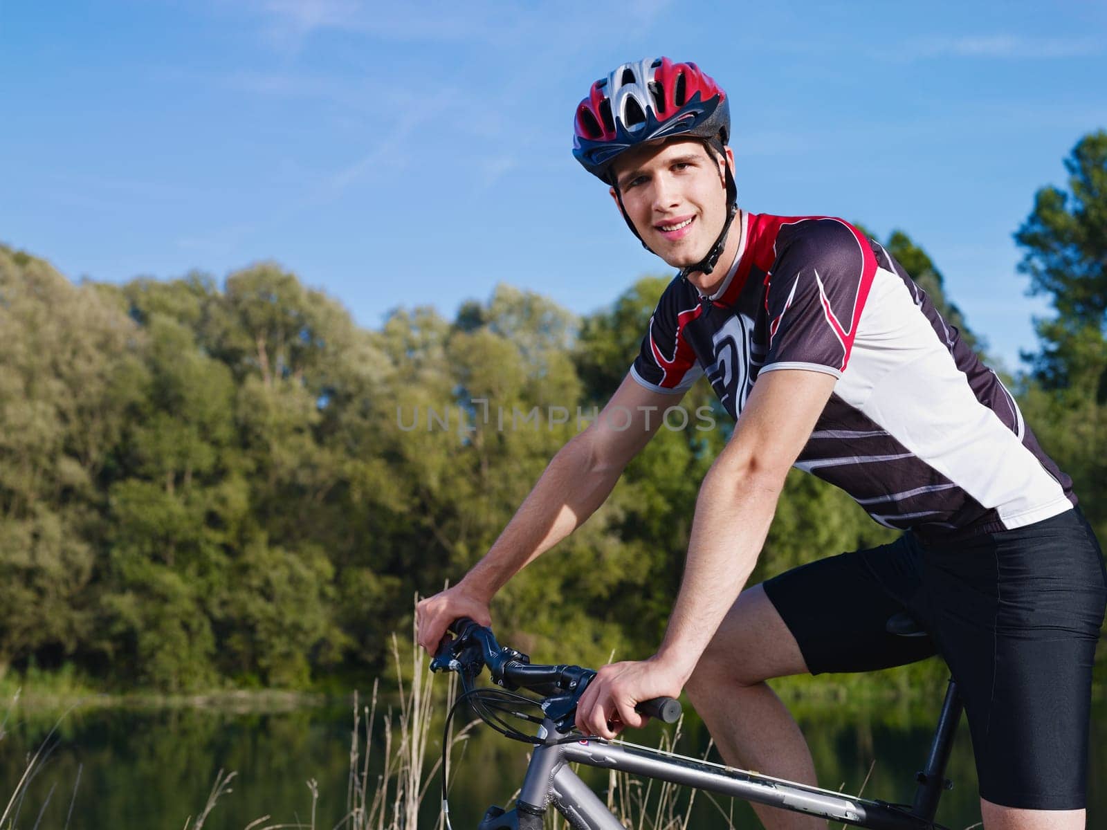 sports activity: young adult cyclist riding mountain bike in the countryside and looking at camera. Horizontal shape, side view, copy space