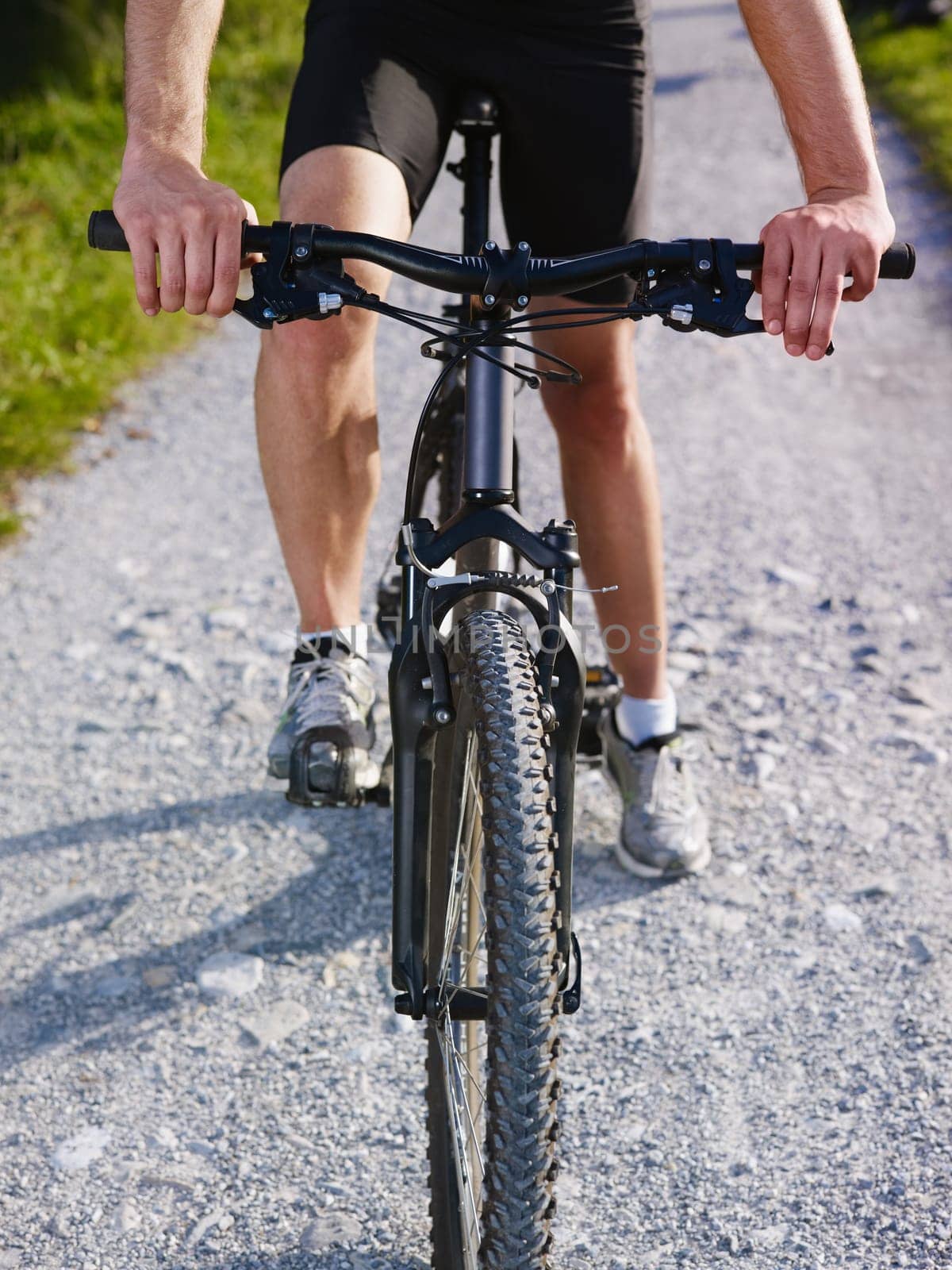 sports activity: young adult cyclist riding mountain bike in the countryside. Vertical shape, cropped view, low section