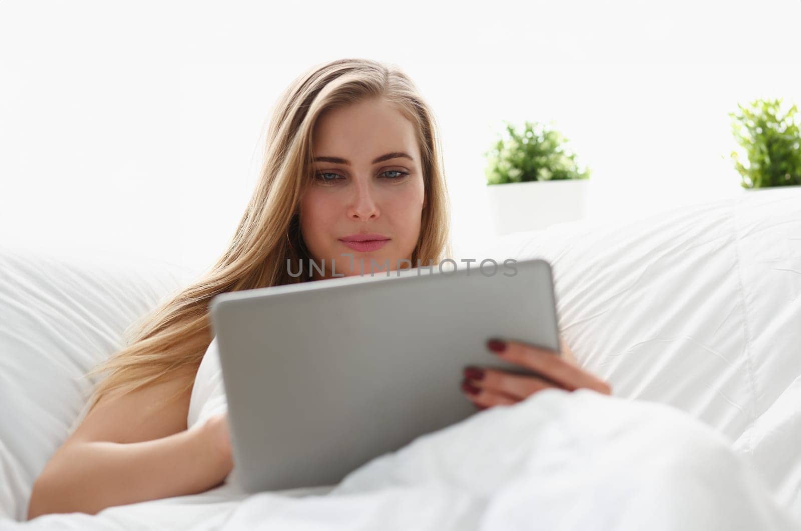 young blond beautiful woman work winh laptop stay in bed early morning