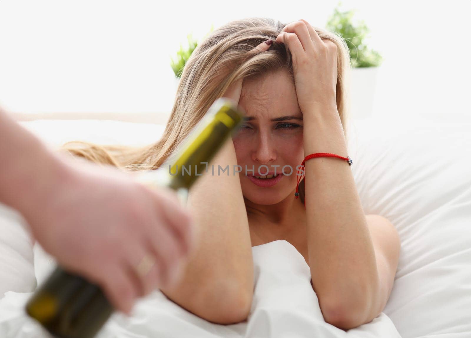 beautiful young blond woman stay in bad is given bottle of wine unhealthy way of life concept