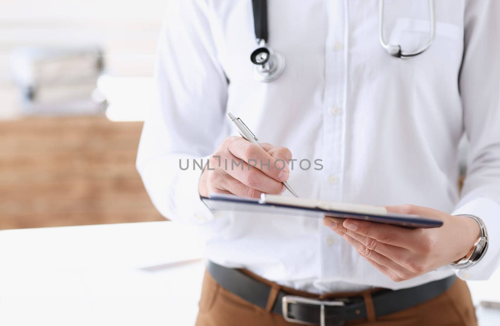 Male medicine doctor hand holding silver pen and clipboard pad closeup. Ward round patient visit check medical calculation and statistics concept physician ready to examine patient
