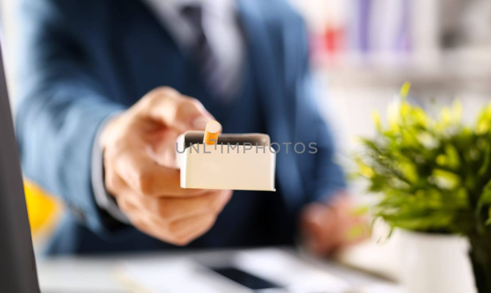 Male arm in suit offer pack of cigarettes to take closeup in office