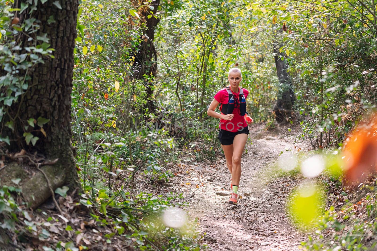 woman practicing trail running in the forest, concept of sport in nature and healthy lifestyle, copy space for text