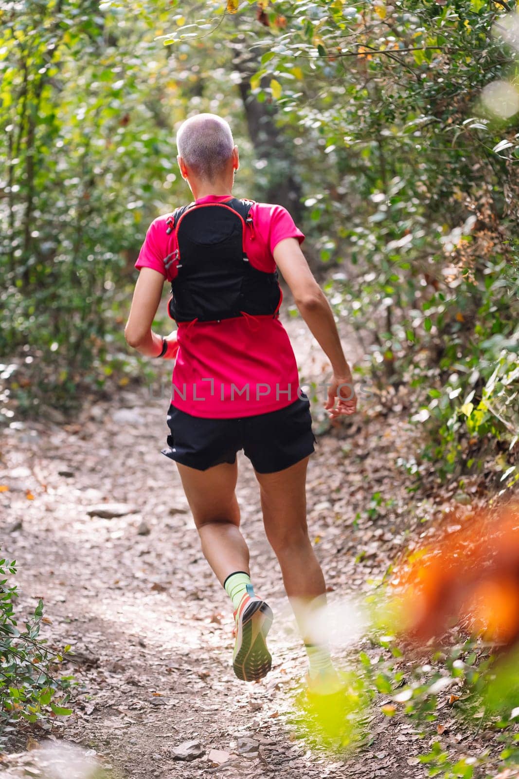rear view of a woman practicing trail running in the woods, concept of sport in nature and healthy lifestyle, copy space for text