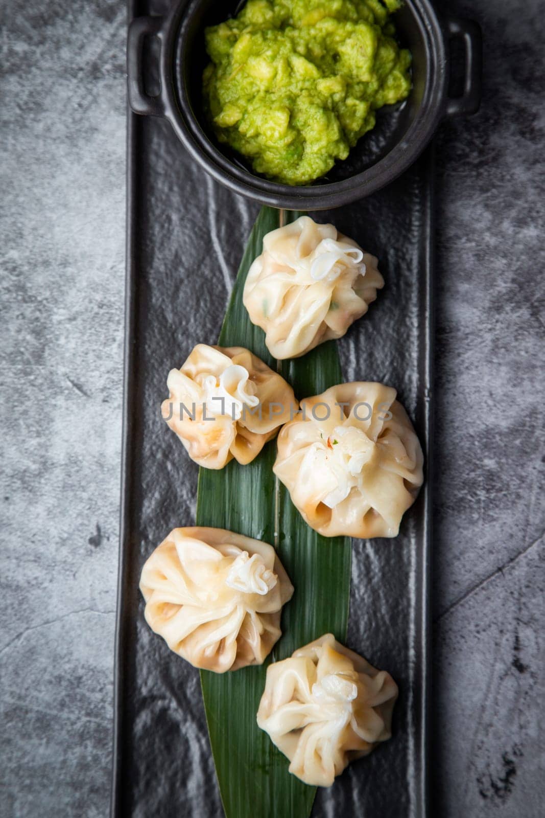 juicy khinkali with sauce on a black board top view by tewolf