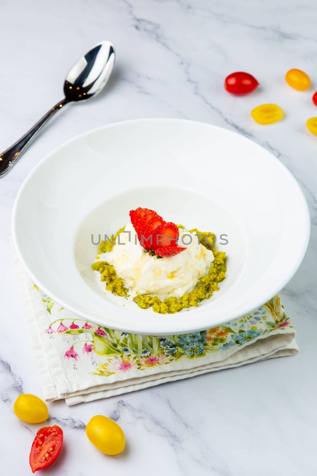 curd dessert with strawberries on top in a white plate on a marble background