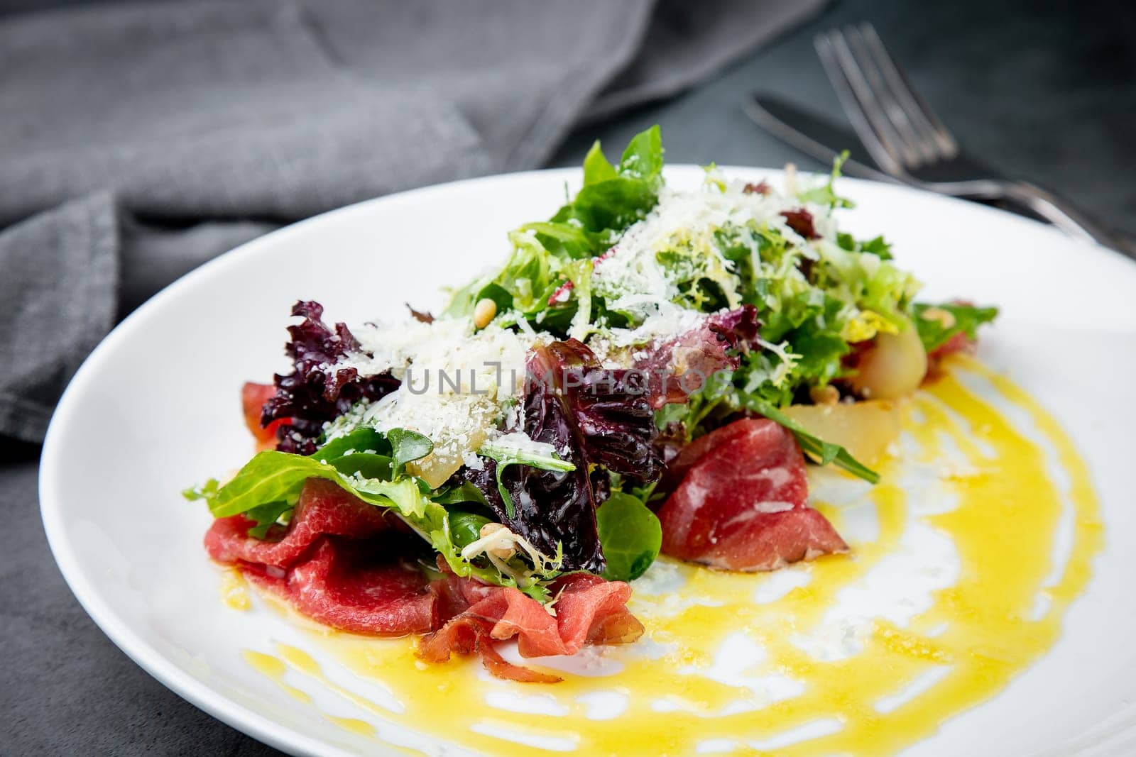 salad with red cabbage, meat, cheese and herbs with sauce in a round plate side view by tewolf