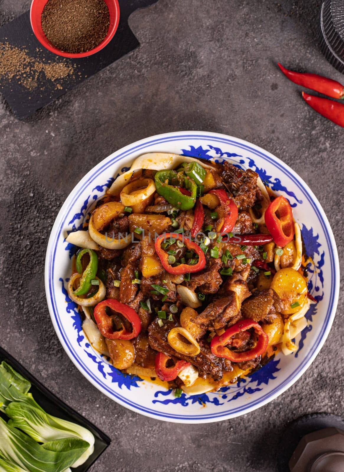 noodles with bell pepper, potatoes, meat and herbs in a plate with a pattern top view by tewolf