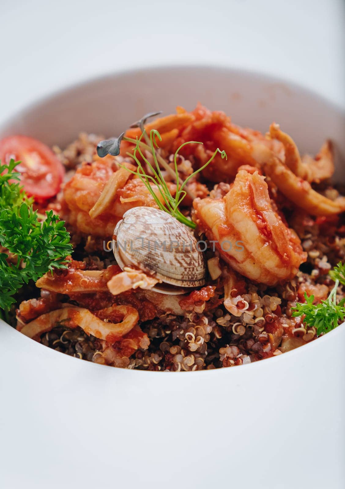 buckwheat with seafood, oyster, tomato and herbs in a deep plate side view by tewolf