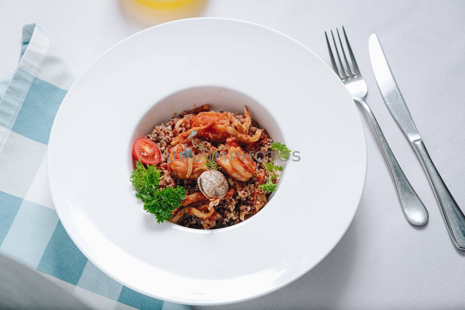 buckwheat with seafood, oyster, tomato and herbs in a deep plate side view by tewolf