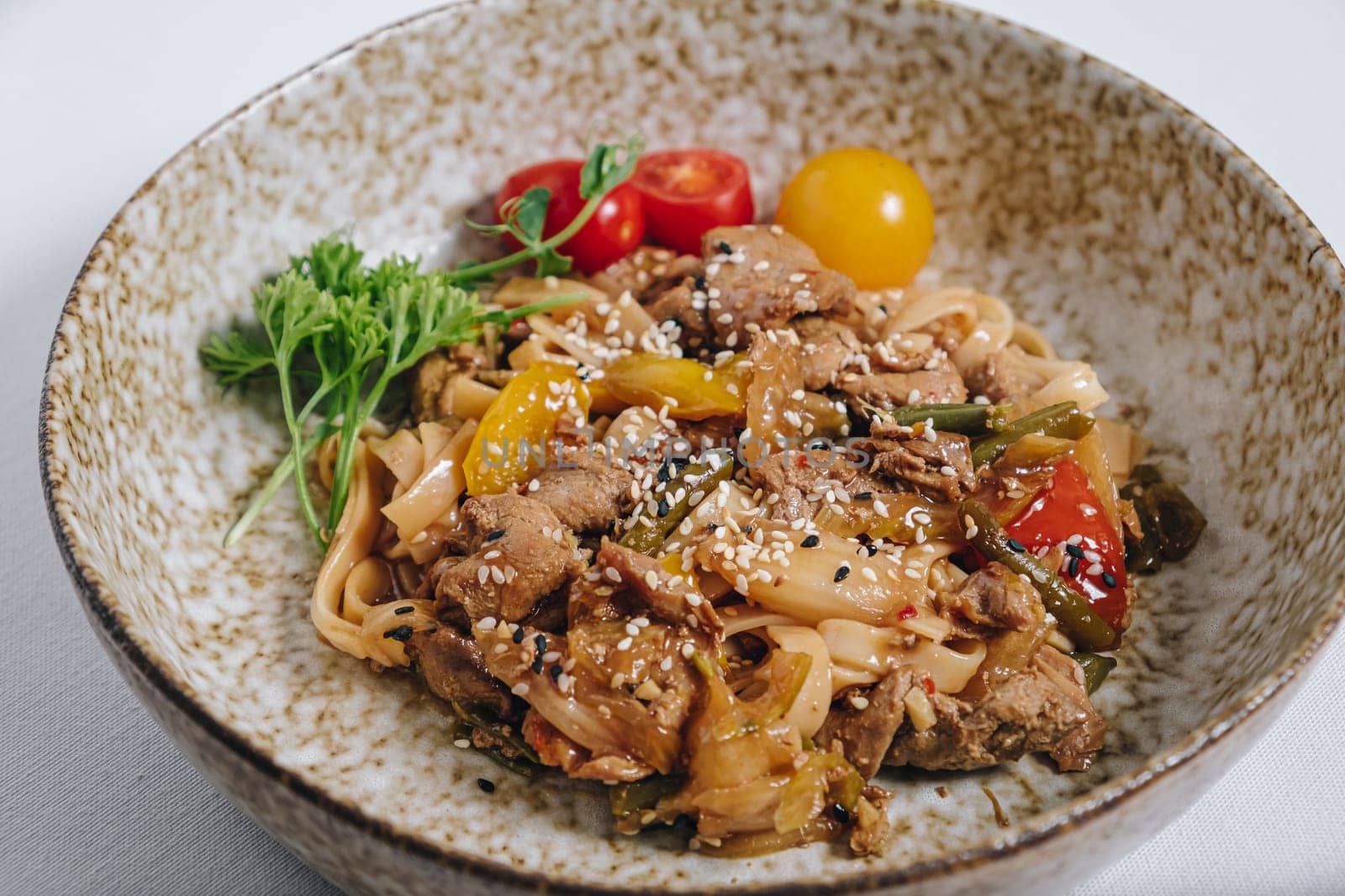 udon noodles with duck meat, herbs, sesame seeds and cherry tomatoes side view by tewolf