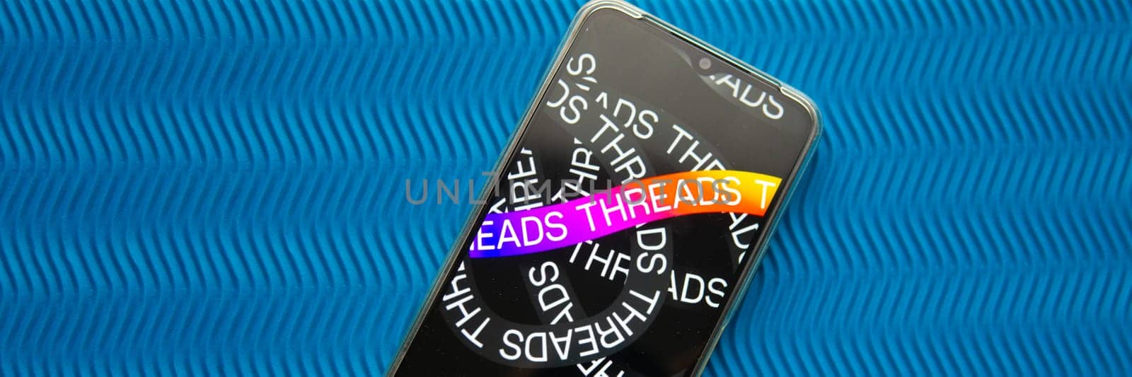 Tver, Russia - July 15, 2023, threads logo on the smartphone screen, on a blue background. The threads icon. The logo of the current application. Threads social network