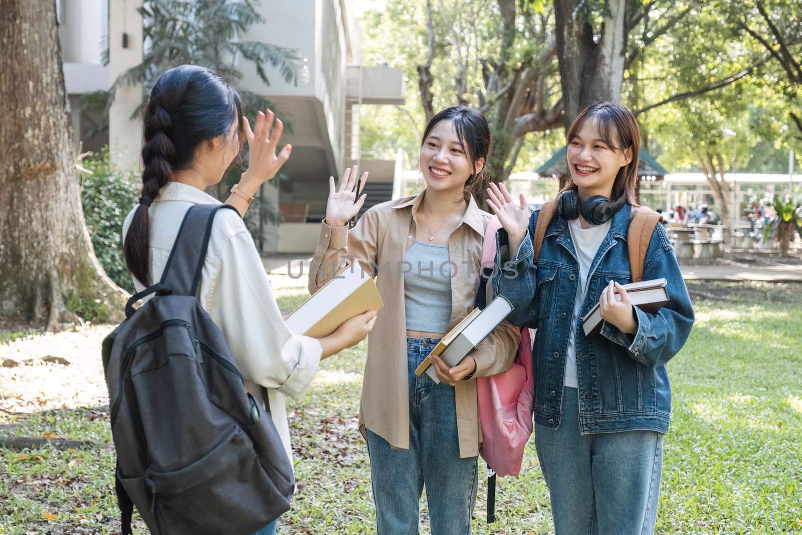 Friendly asian female college student waving hand while greeting her classmate. Education and youth lifestyle concept by wichayada