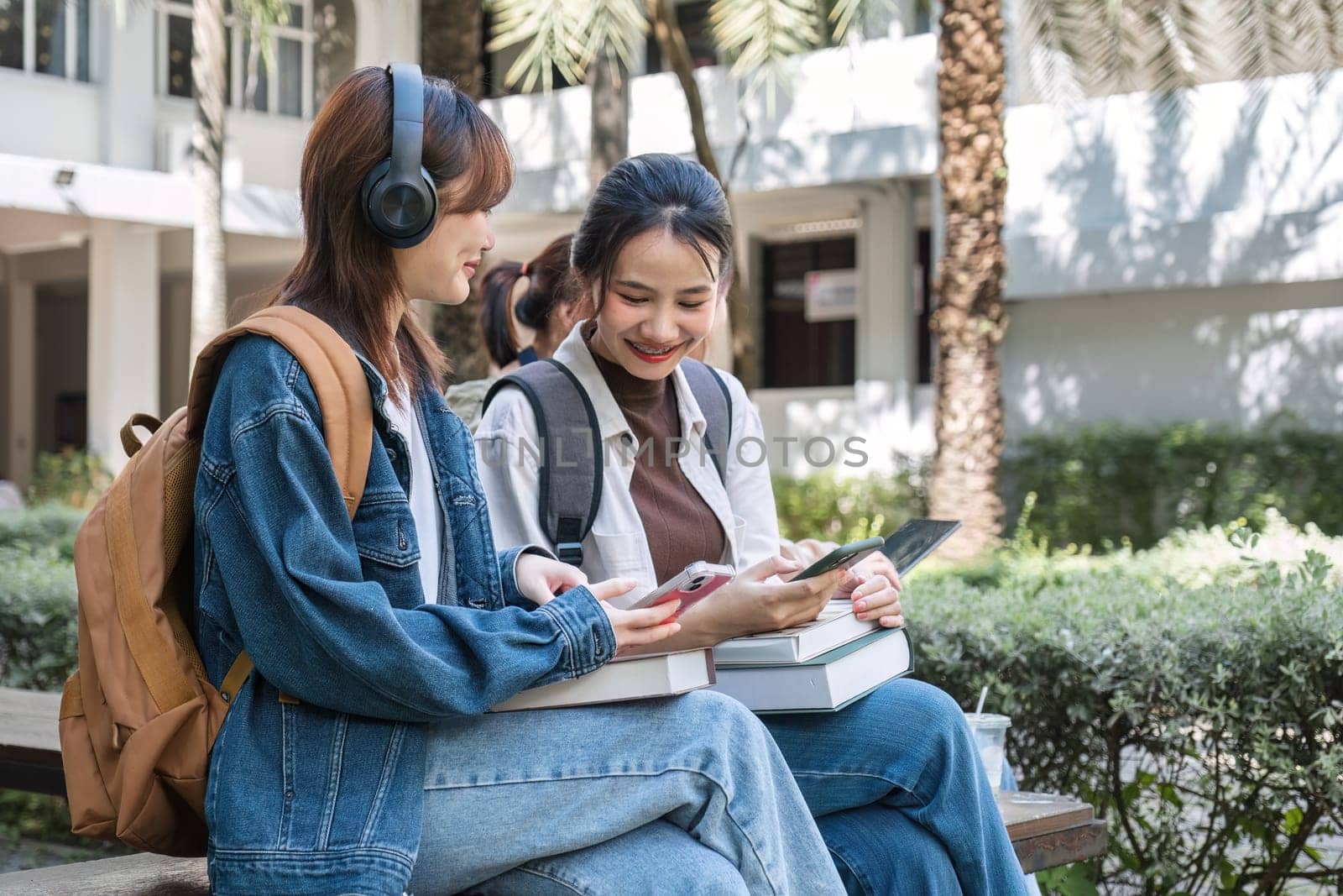 Group of cheerful Asian college students or friends laughing together while sitting in university. by wichayada