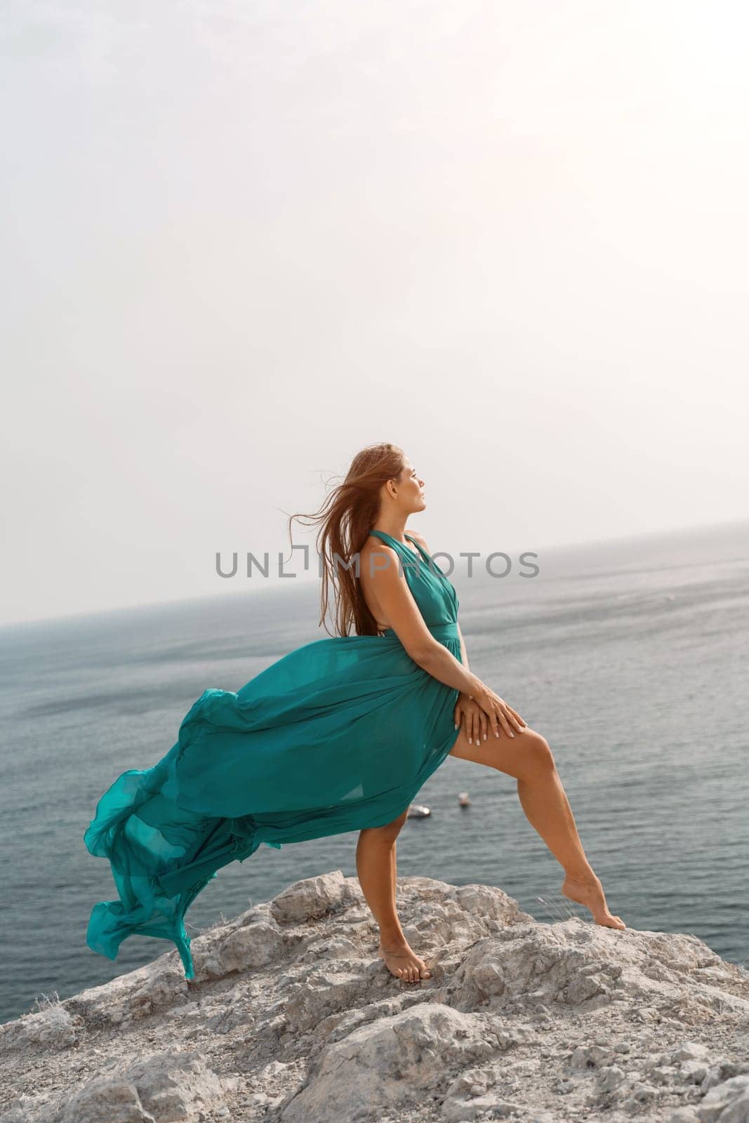 Woman sea trevel green dress. Side view a happy woman with long hair in a long mint dress posing on a beach with calm sea bokeh lights on sunny day. Girl on the nature on blue sky background. by Matiunina