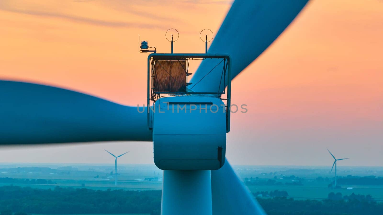 Close up of motor on wind turbine with orange sunset aerial of wind farm by njproductions