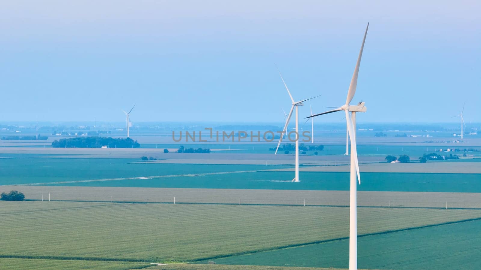Image of Aerial wind farm standing in farmland with green and light green crops