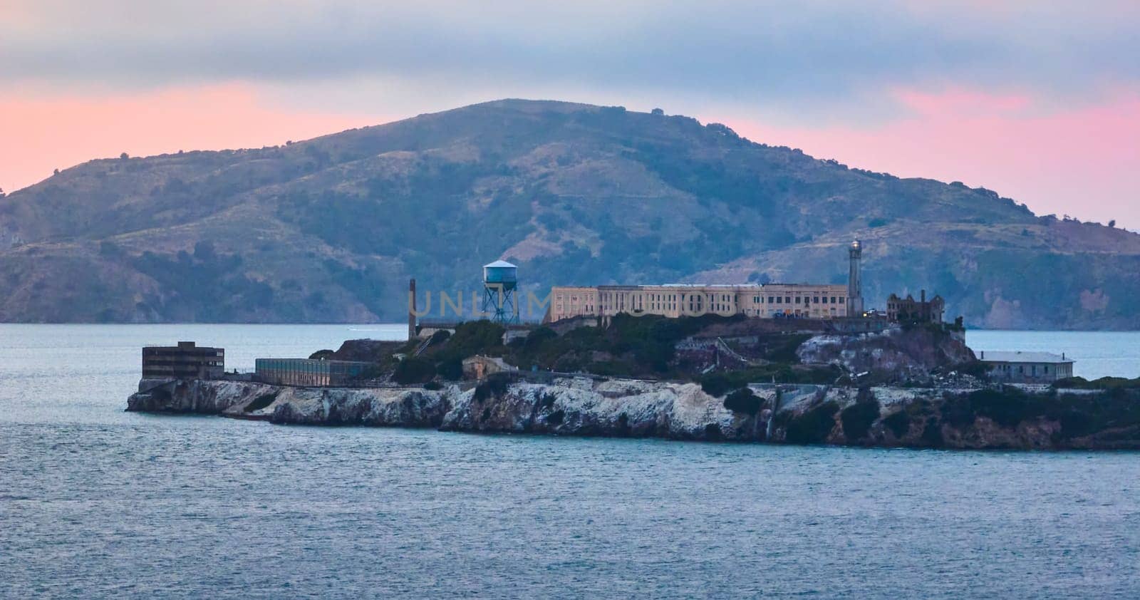 Image of Alcatraz Island with pink glow over island and distant mountain aerial
