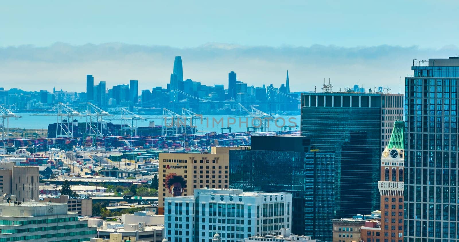 Oakland aerial over city skyscrapers with zoomed in view of distant San Francisco downtown by njproductions
