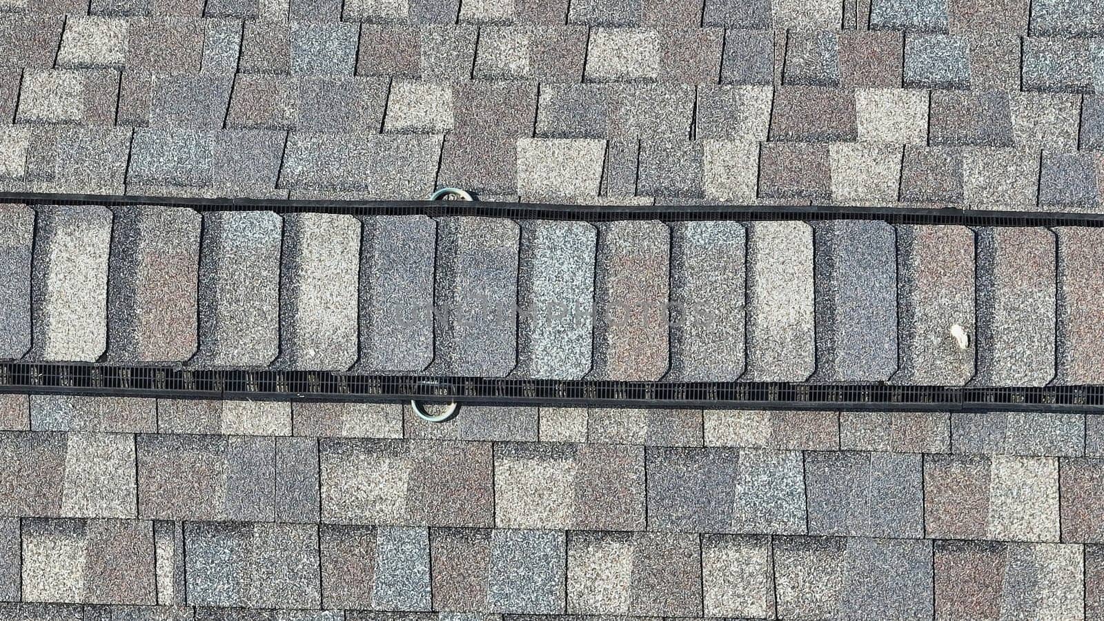 Straight down aerial over earthtone shingles on roof with two roof anchor rings by njproductions