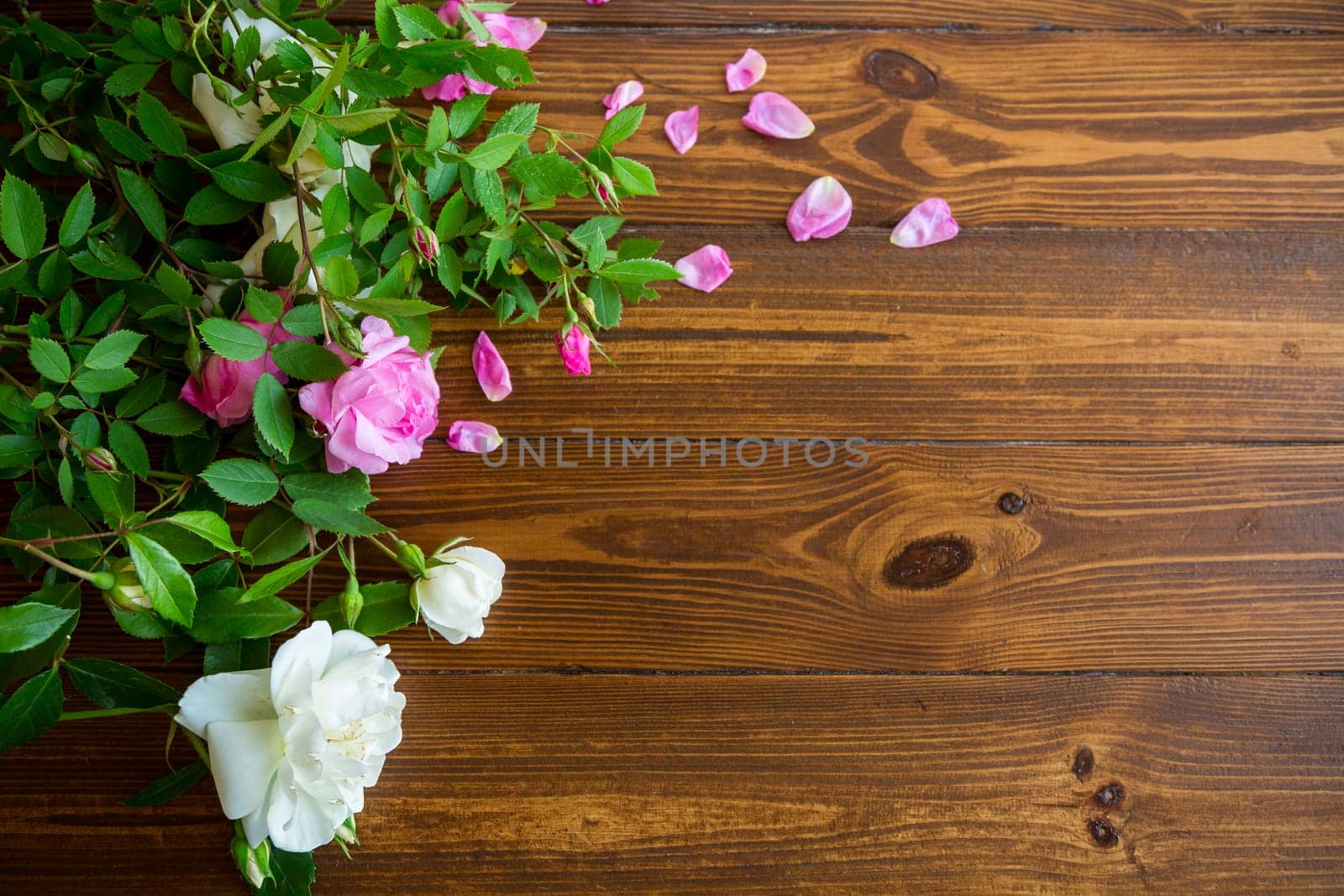 Floral background of pink and white roses on a dark wooden table