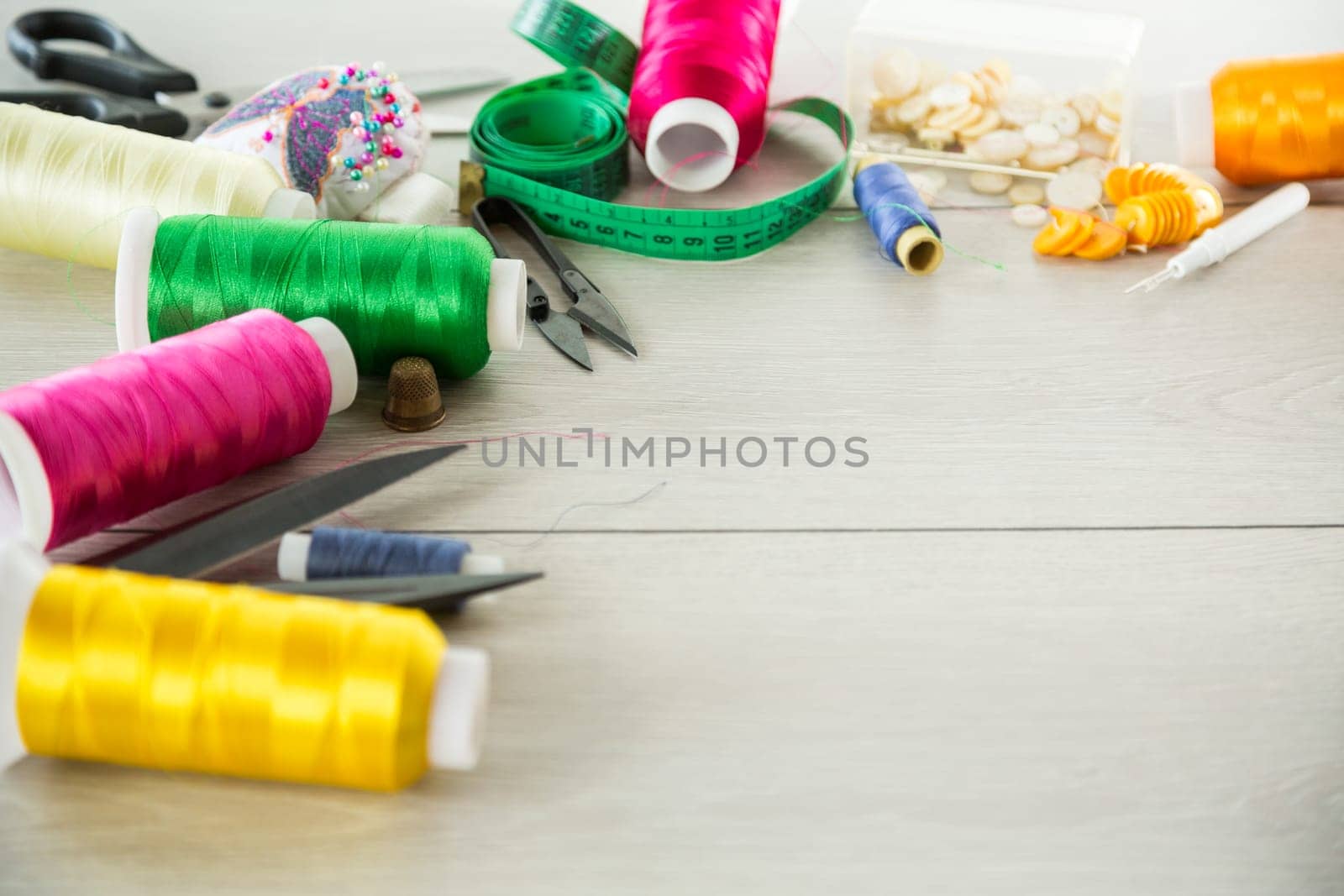 a set of tools and threads for sewing clothes, on a wooden background.