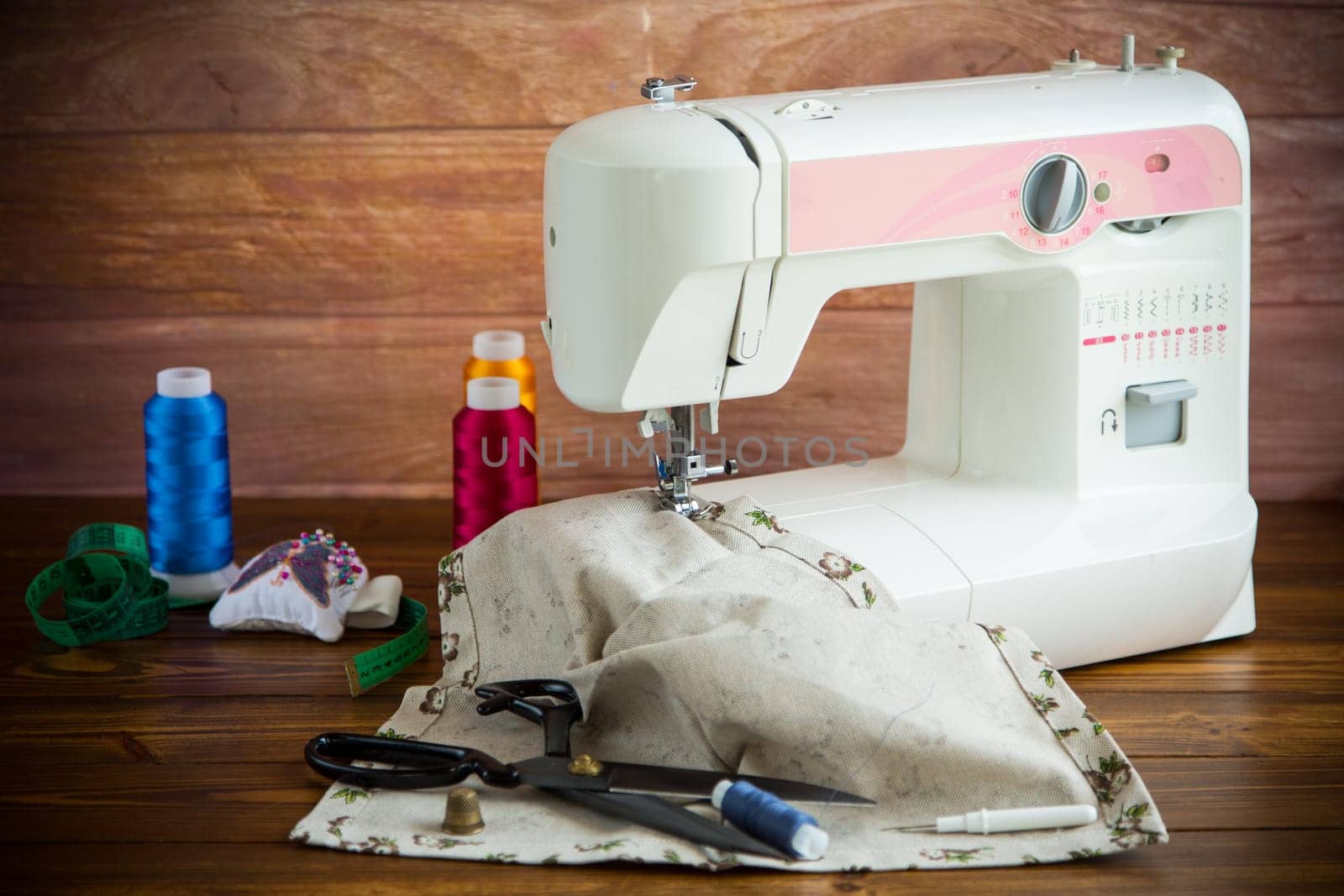 Sewing machine with fabric and threads for sewing, close-up. The working process by Rawlik