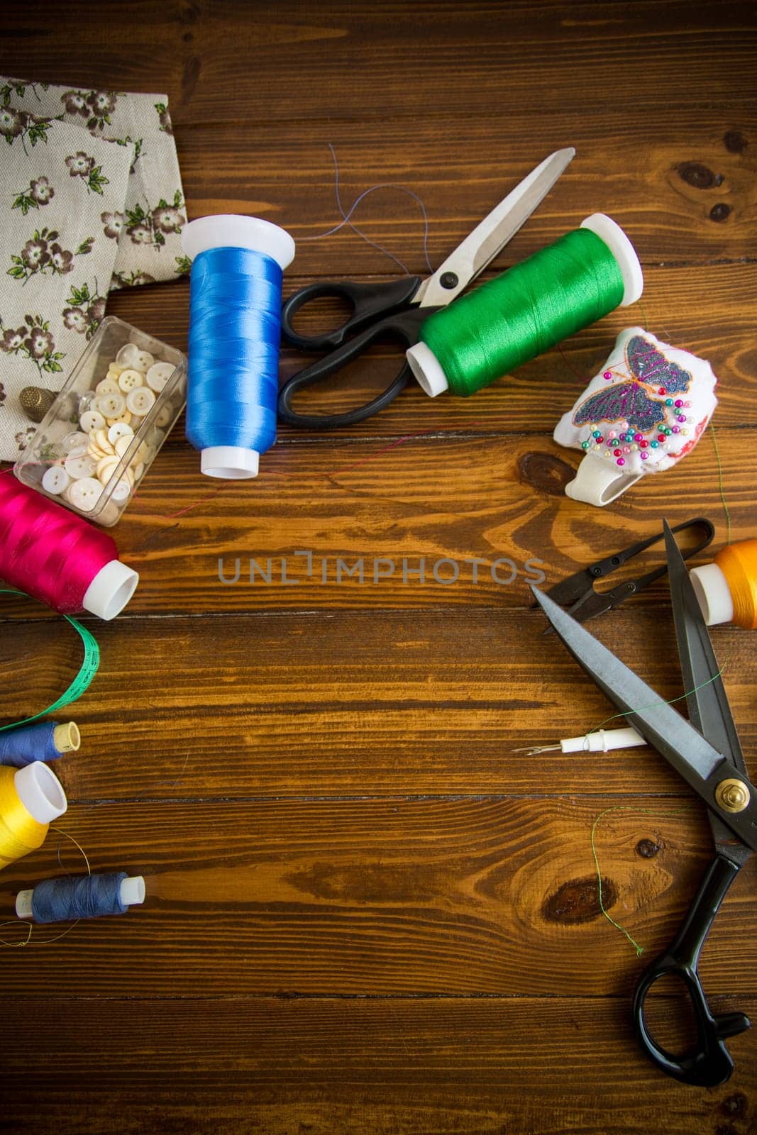 a set of tools and threads for sewing clothes, on a wooden background.