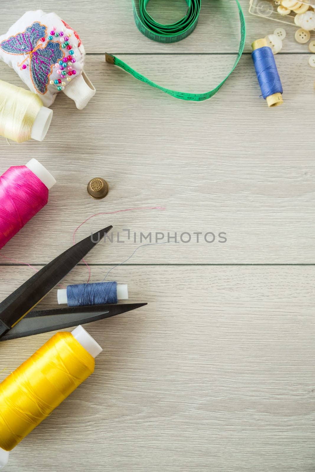 a set of tools and threads for sewing clothes, on a wooden background.