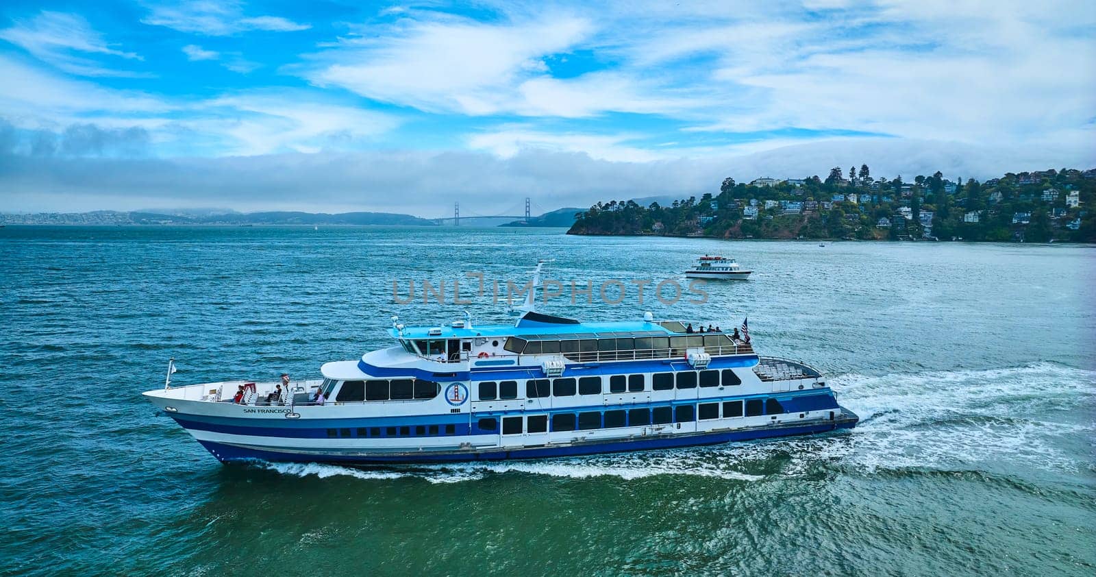 Image of Side view Golden Gate Ferry with smaller boat near Tiburon and Golden Gate Bridge in distance aerial