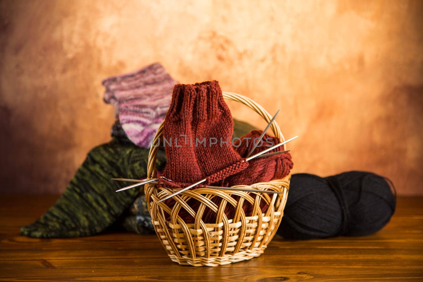 Colored yarn, knitting needles and other items for hand knitting on a dark wooden table.