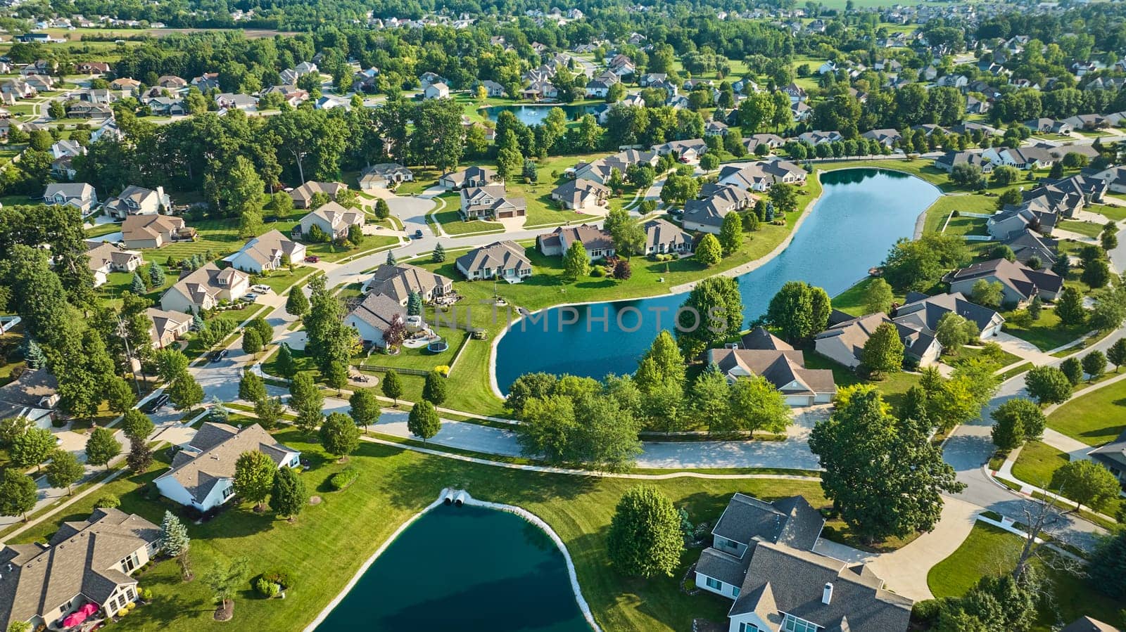 Image of Neighborhood aerial with hundreds of houses on bright sunny day with ponds