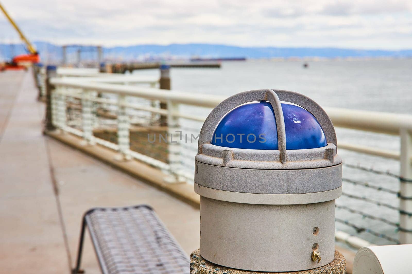 Image of Blue light on heavy duty harbor railing with blurry background of San Francisco Bay