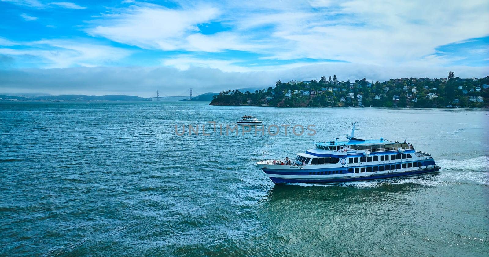 Image of Golden Gate Ferry with smaller boat cruising near Tiburon and Golden Gate Bridge in distance aerial