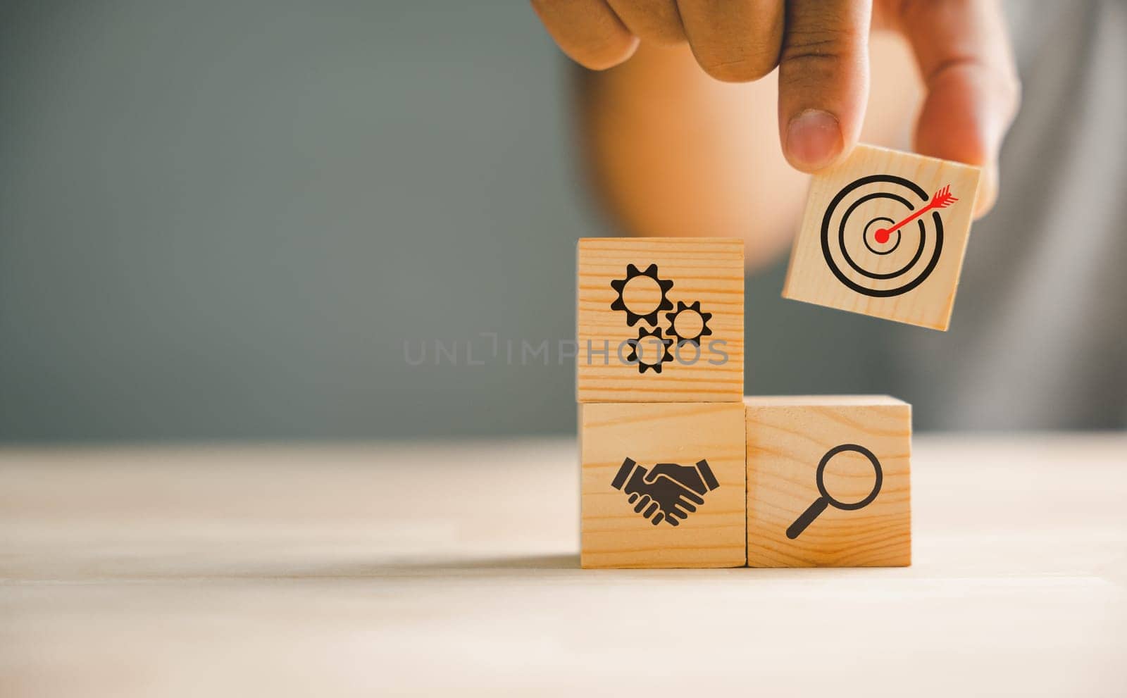 Hand skillfully arranging wood blocks in a strategic stacking, symbolizing business strategy and Action plan. Targeting the concept of business development and growth.