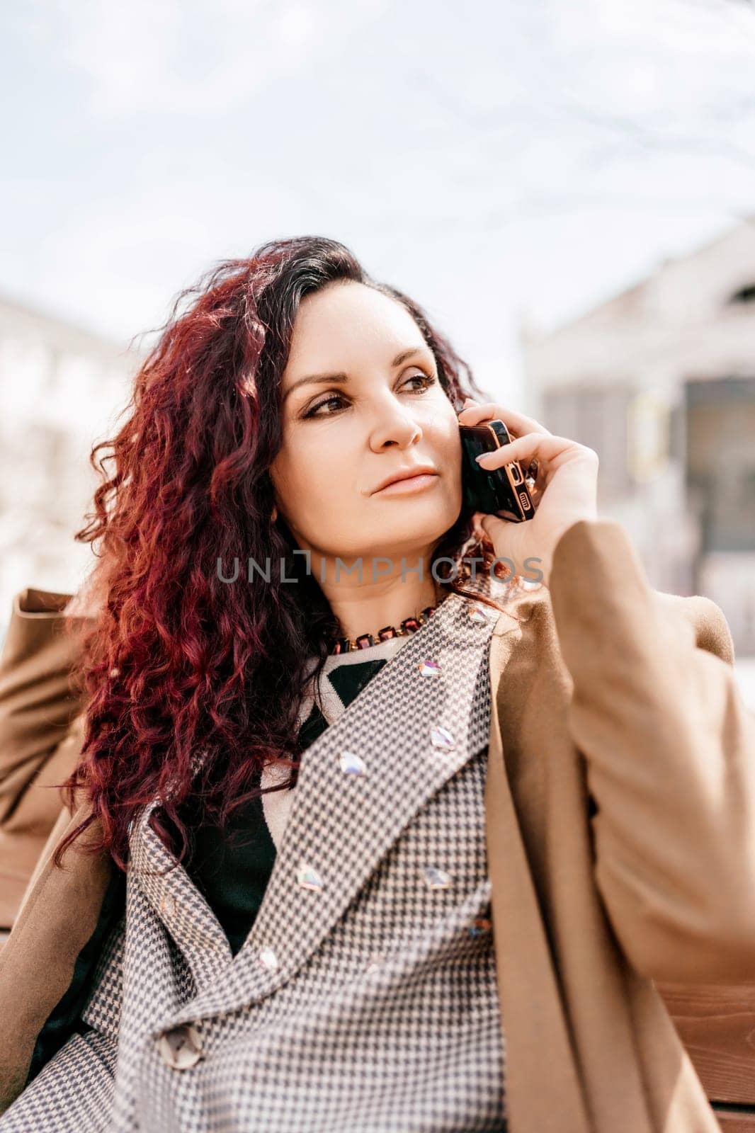 brunette businesswoman talking mobile phone with client. Woman managing business talking via mobile phone sitting by Matiunina