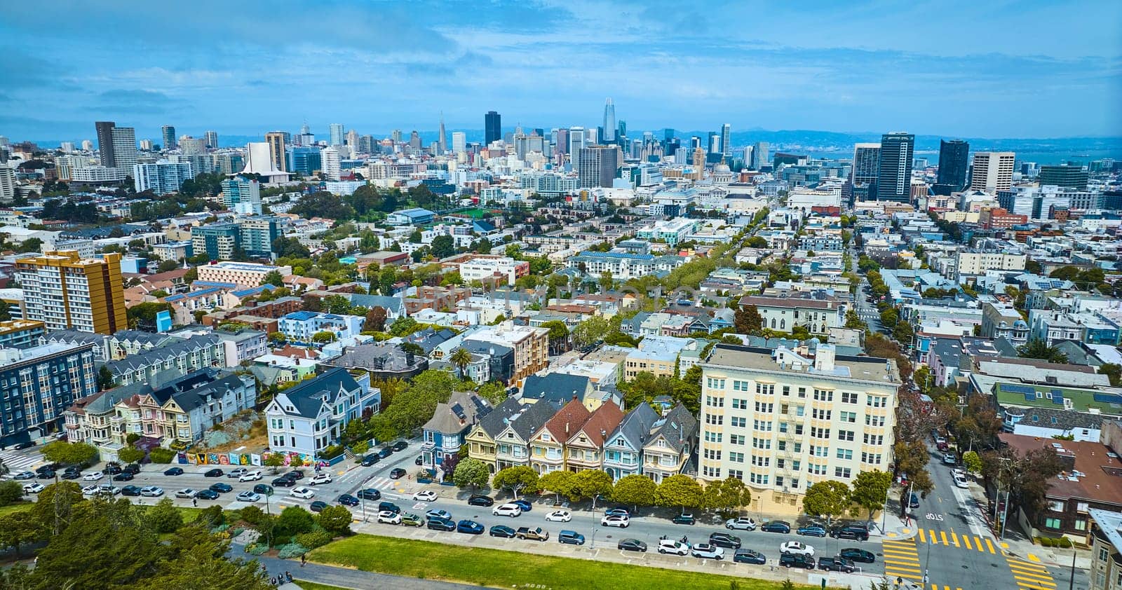 Image of Aerial The Painted Ladies with wide view of San Francisco city skyscrapers under pretty blue sky