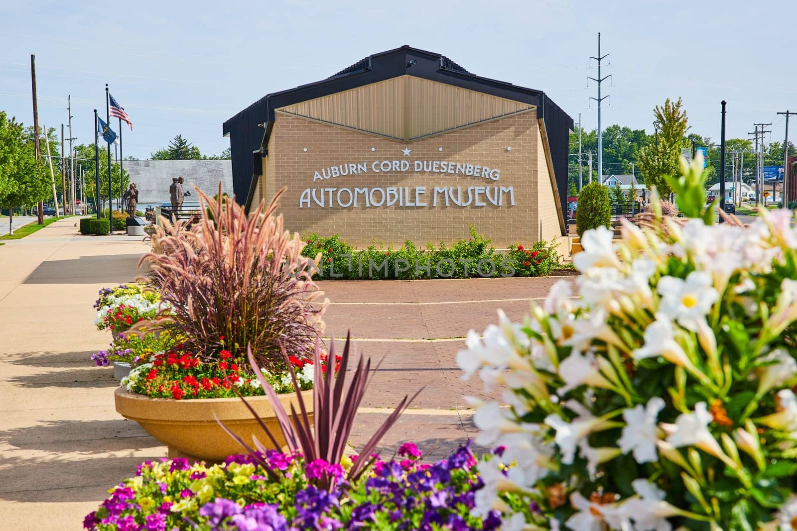 Image of ACD automobile museum sign behind multiple flower pots with colorful assortment of flowers