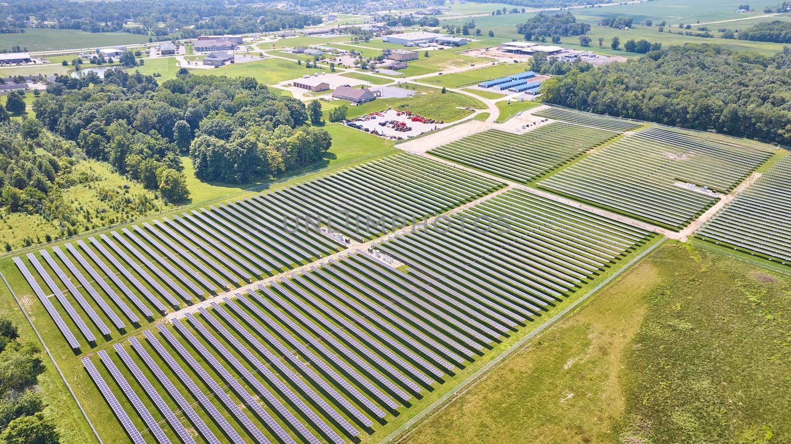 Image of High up view of solar farm in grassy field on bright summer day