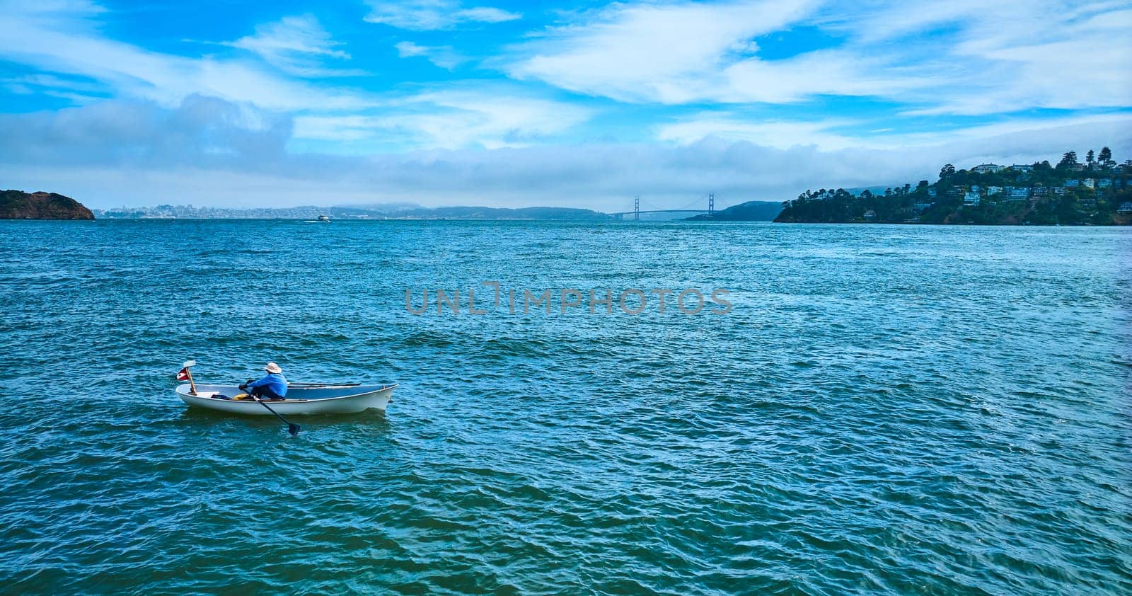Image of Aerial person rowing rowboat across San Francisco Bay toward Tiburon with Golden Gate Bridge