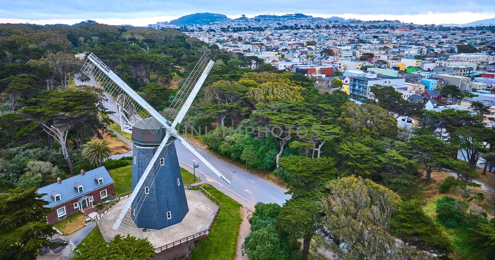 Image of Aerial slate blue murphy windmill with white blades with home and trees beside large city