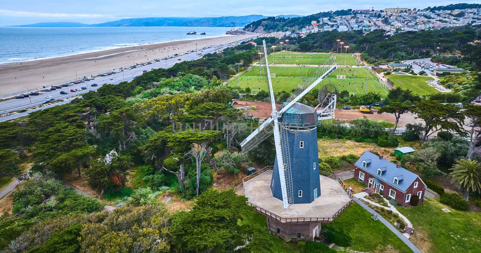 Image of Murphy windmill beside small home and active soccer fields with city and ocean aerial