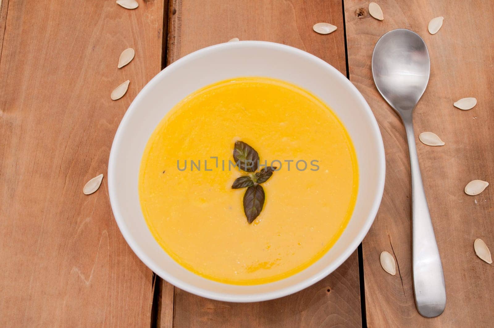 Bowl of Butternut Squash Soup and Spoon on Old Wooden Table