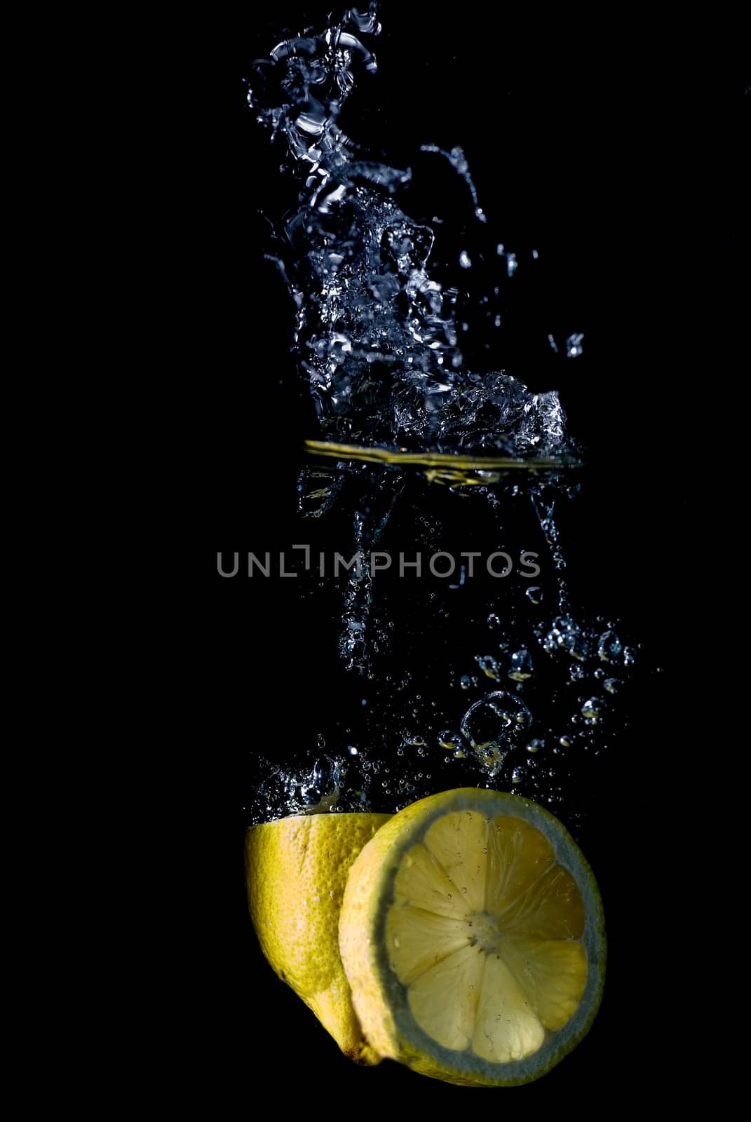 Lemon splashing on a water surface with a black background.