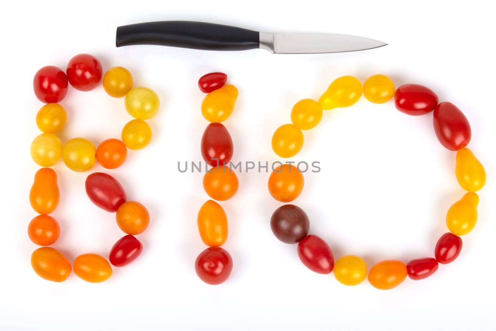 The lettering BIO is made of small colorful organic tomatoes with a knife on the side of the head. The word "organic"" set of small colored organic tomatoes with a knife on the head side."