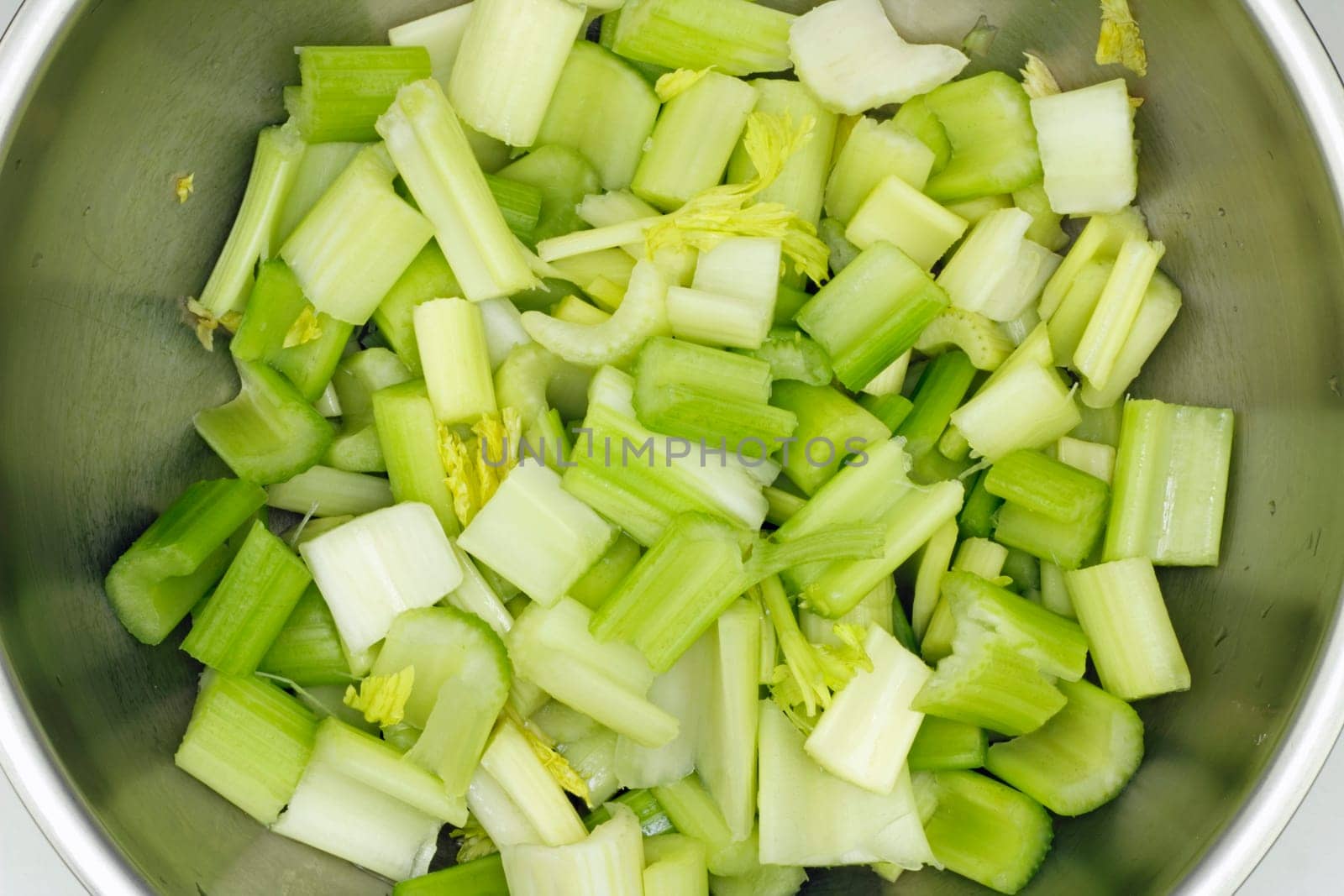 Chopped celery in a stainless steel bowl.