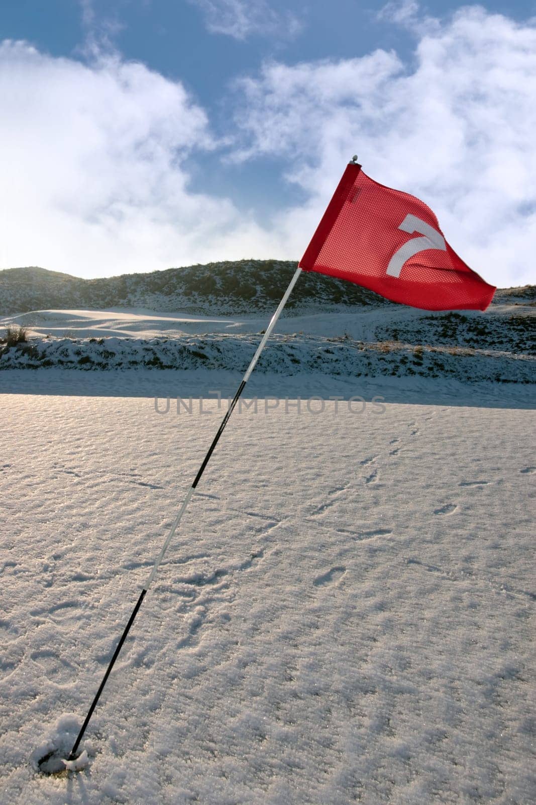 flag on a snow covered links golf course in ireland in winter