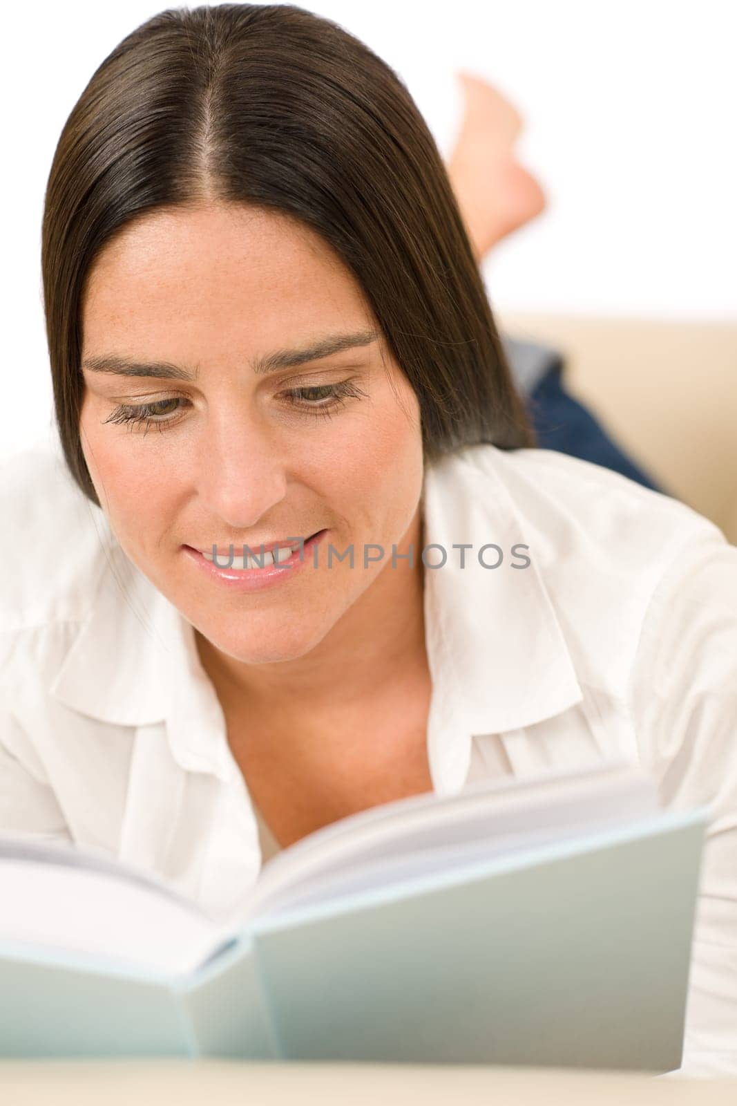Attractive mid-aged woman read book on sofa in lounge