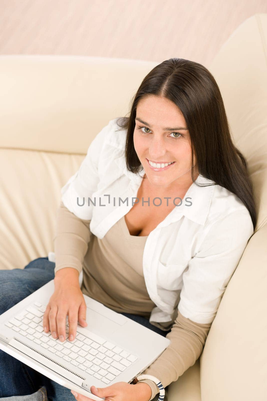 Attractive woman with laptop sitting on couch smiling